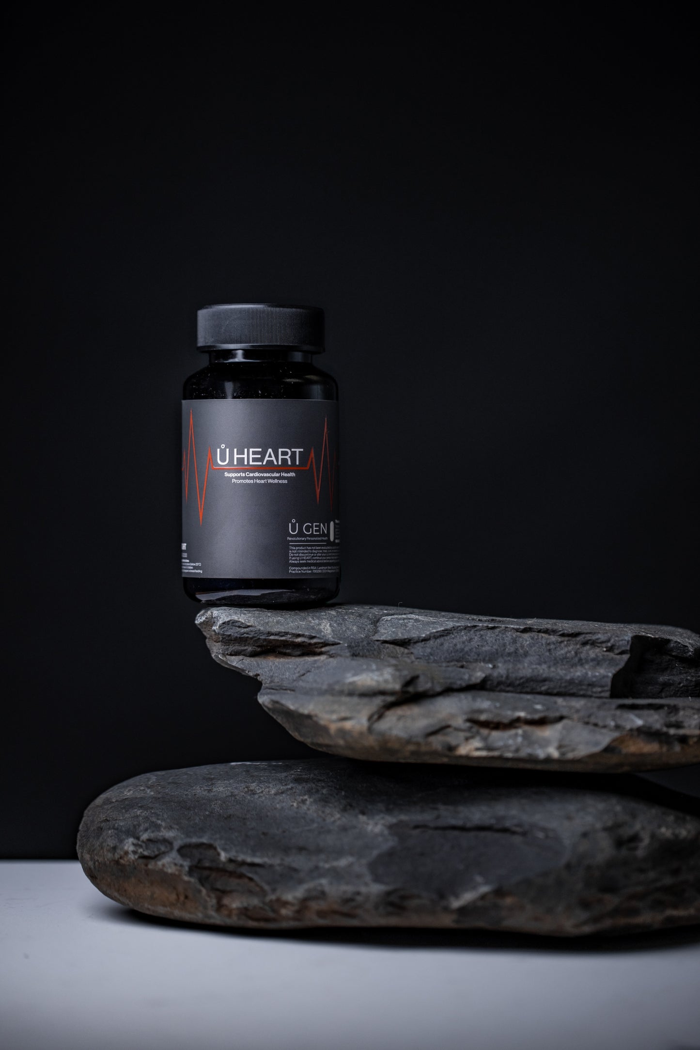 A bottle of U Gen Wellness U heart supplements sitting on a rock.