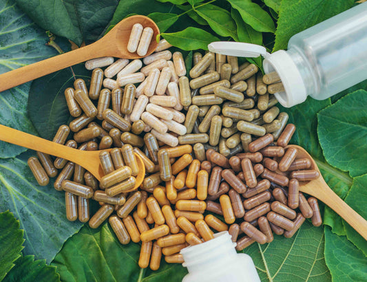 Vegan capsules laid out on cabbage leaves and surrounded by wooden spoons.