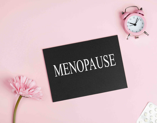 A photo of a clock, a flower, and sign that reads "menopause".